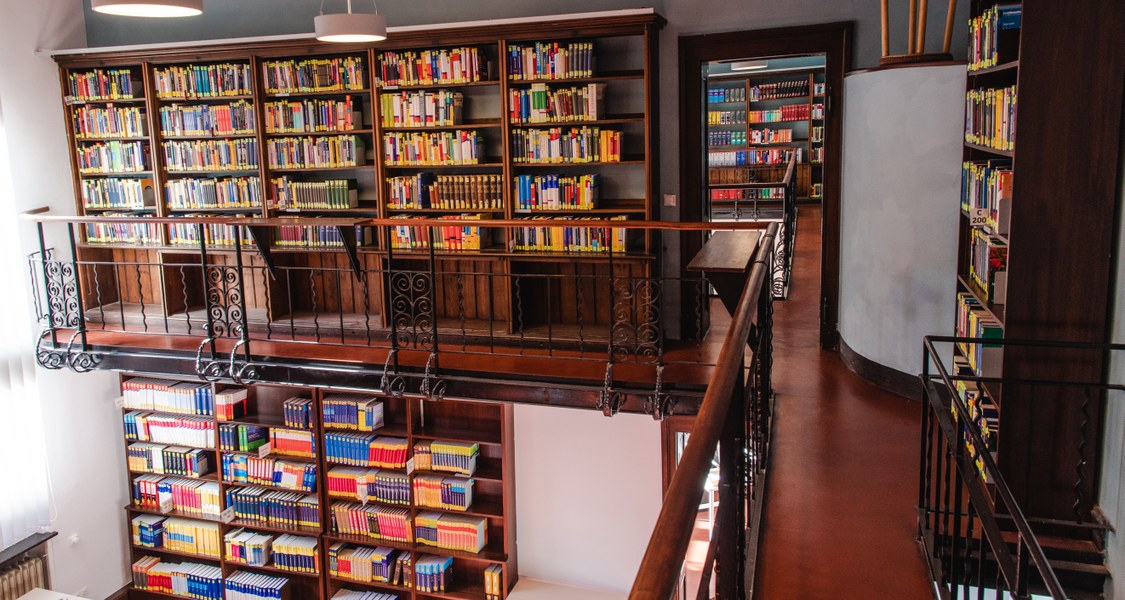 Bücher in Bücherregalen auf zwei Stockwerke verteilt.