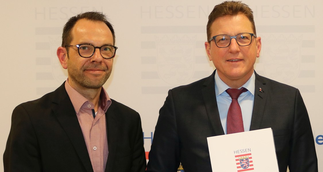 Halbtotale mit zwei Personen und dem Dokument des Förderbescheids