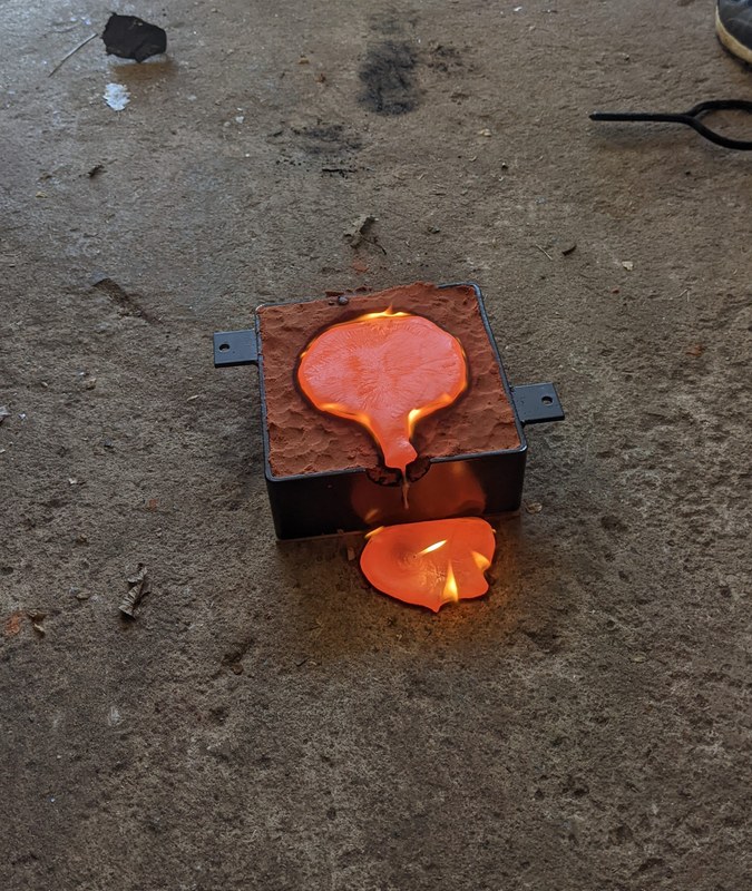 Eine kreisförmige Form aus Ölsand ist voller rot glühender, flüssiger Bronze