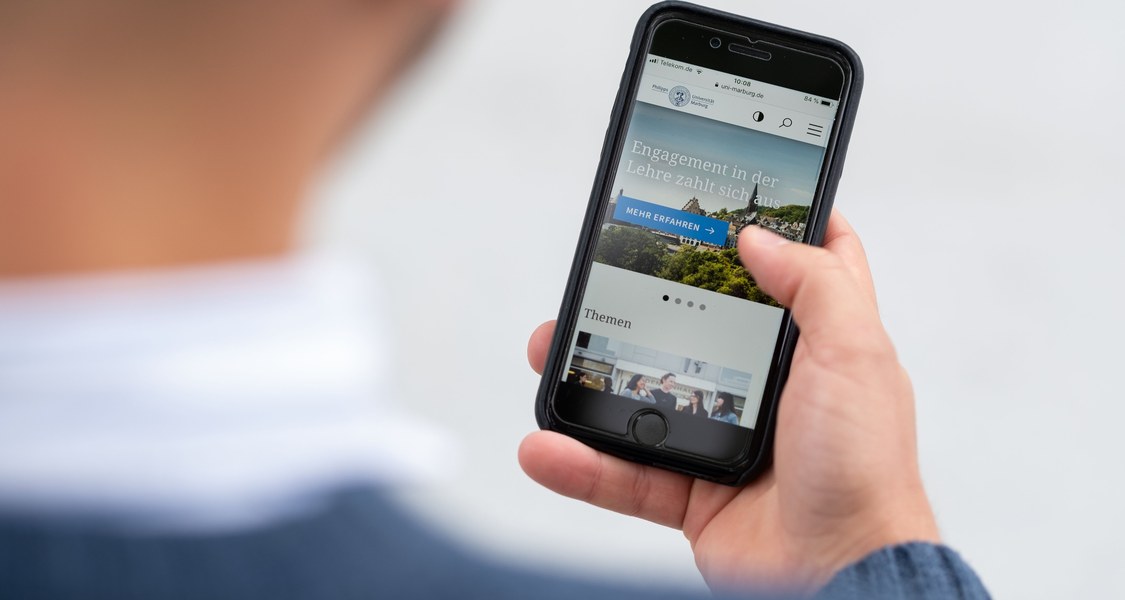 Mann hält ein Smartphone in der Hand.
