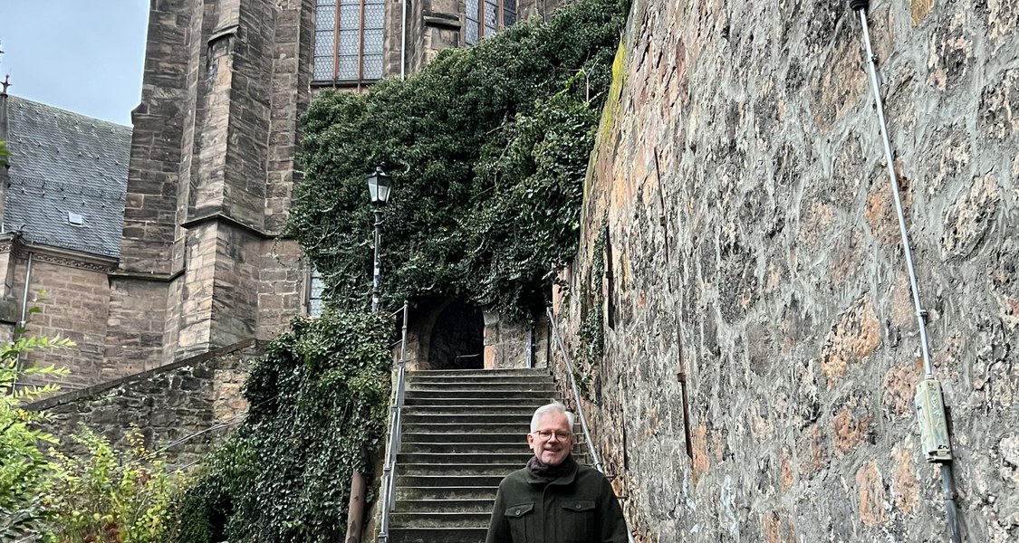 Universitätsprediger Karl Pinggéra stehend vor der Dominikanertreppe.