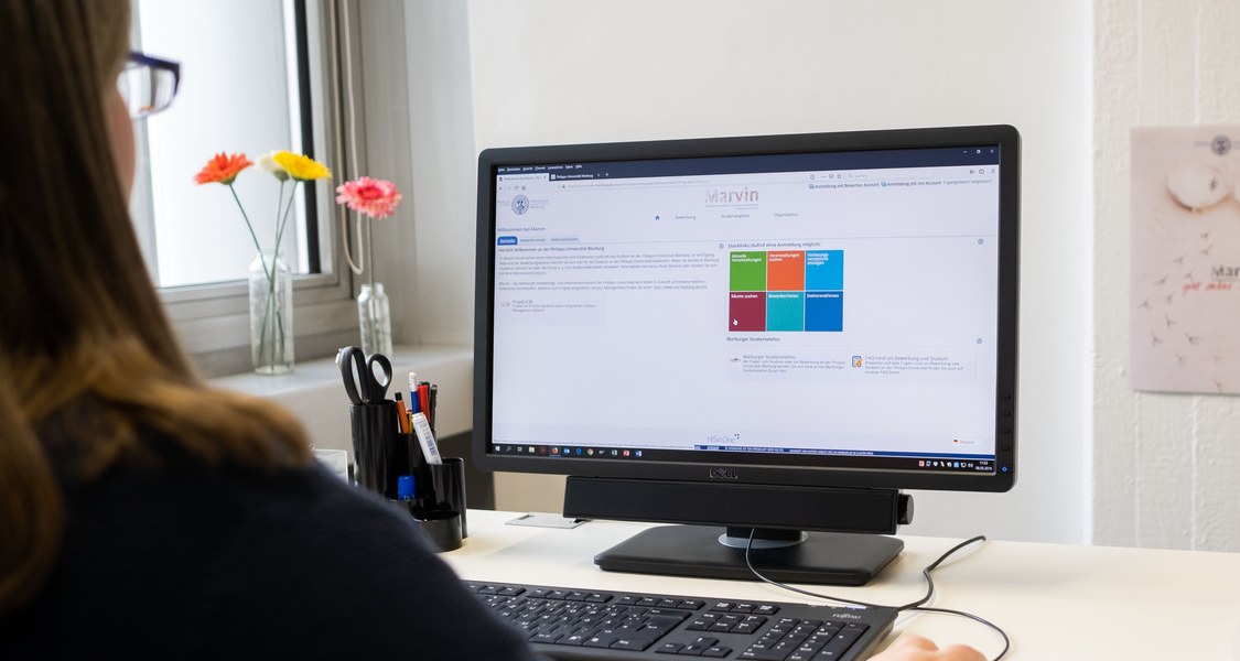 Eine junge Frau sitzt am PC und bearbeitet ihre digitale Bewerbung über MARVIN, das Marburger Verwaltungs- und Informationssystem der Philipps-Universität Marburg.
