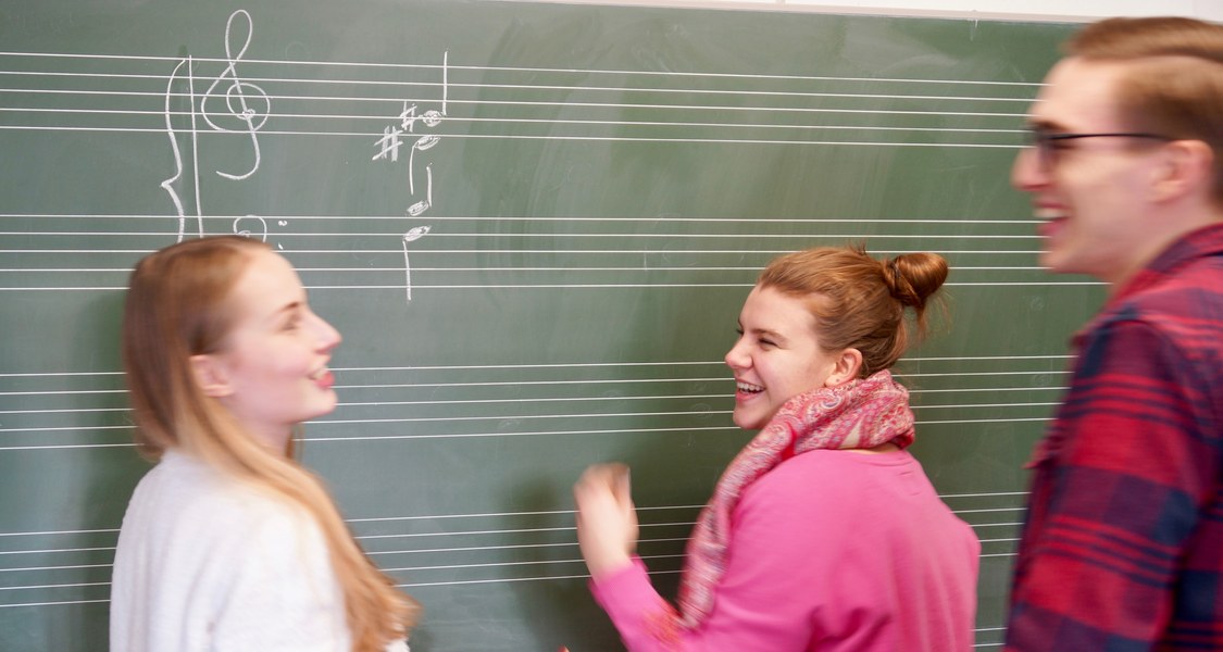 Drei Studierende vor Notentafel