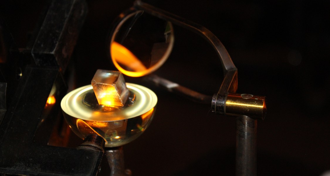 Mit dem Abbe'schen Kristallrefraktometer wurden zu Beginn des 20. Jh. die optischen Eigenschaften von Kristallen untersucht. 
Vor allem Effekte wie die Doppelbrechung standen im Fokus. Das Bild zeigt die Vermessung eines Kalkspatkristalls.