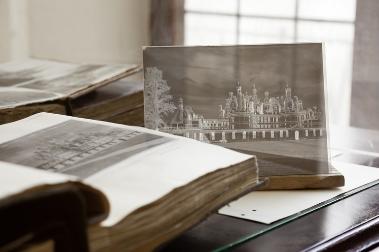 Fotoscheibe eines Negativs neben Büchern  mit Abbildungen älterer Fotographien