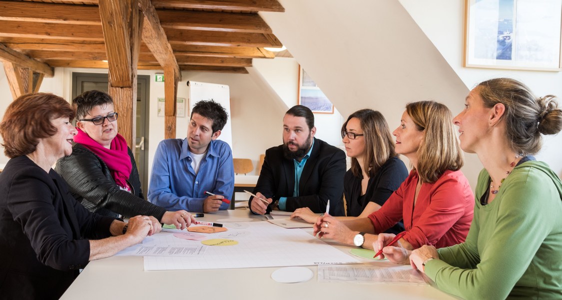 Personen sitzen am Tisch und diskutieren