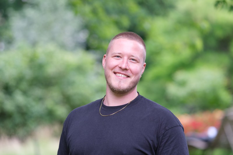 Talentscout Basti in schwarzen T-Shirt vor grünem Hintergrund im Alten Botanischen Garten.