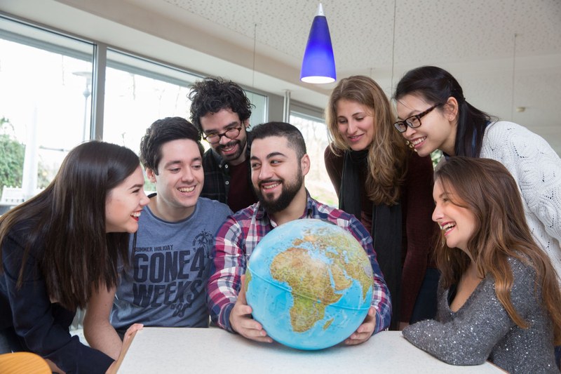 Several students gathered around a globe.