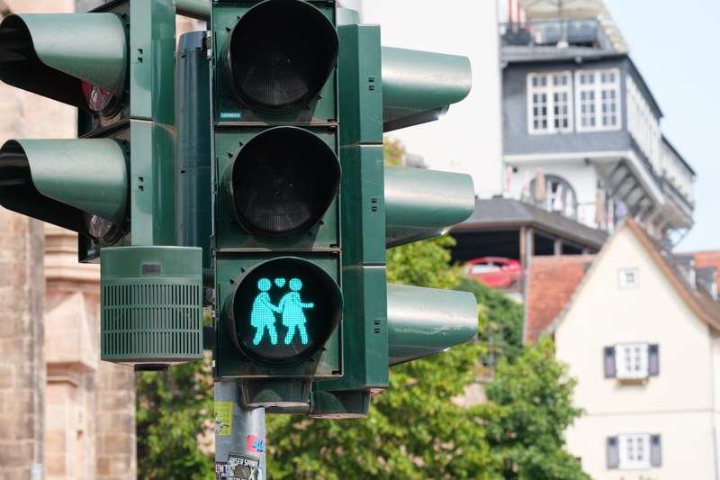 A green pedestrian traffic light at the Old University showing two figures in dresses holding hands.